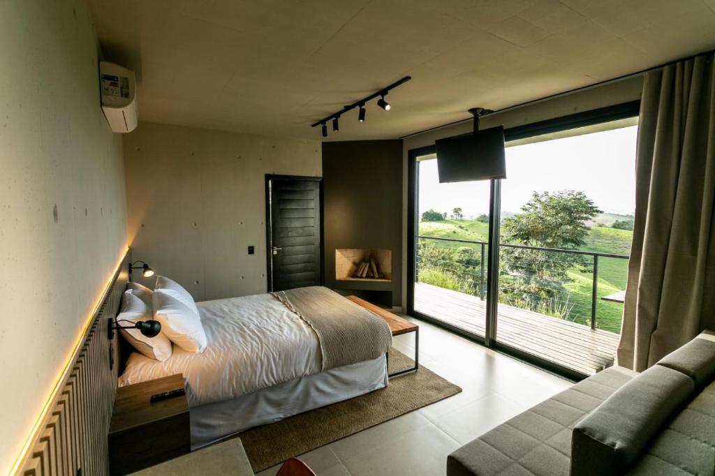 Quarto da Pousada Casa Bambu em Cunha com cama de casal, sofá e varanda com vista para montanhas