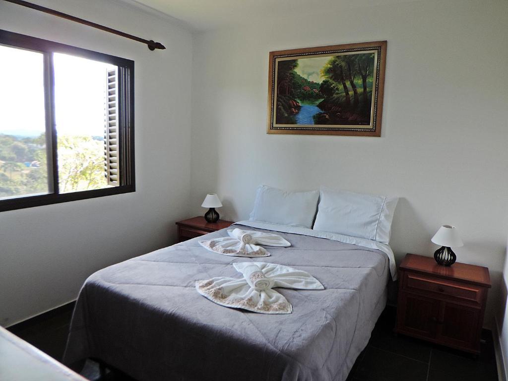 Quarto da Pousada São Bento em Cunha com cama de casal, mesa lateral e janela com vista para área verde
