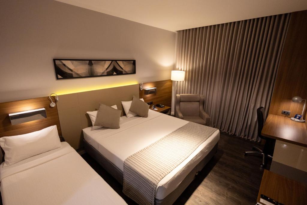 Quarto do JL Hotel by Bourbon com cama de casal, cama de solteiro e iluminação moderna