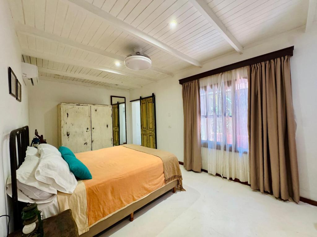 Quarto do Rinco Escondido B&B com cama de casal, armário antigo e cortinas claras
