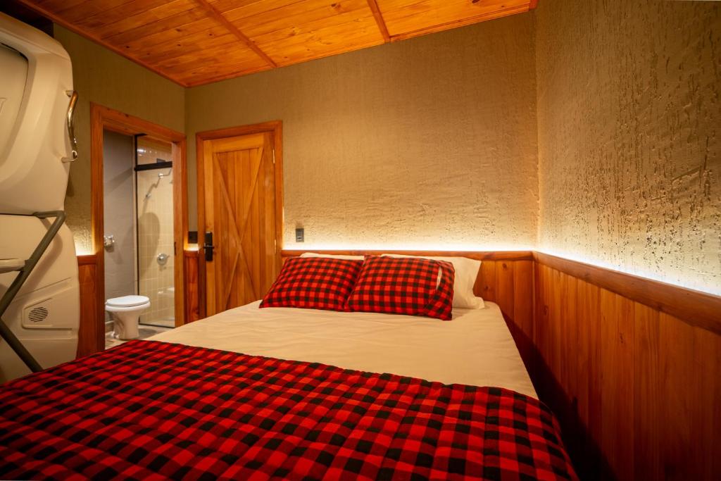 Quarto do The Lodge Iguassu com cama de casal e roupa de cama xadrez vermelha