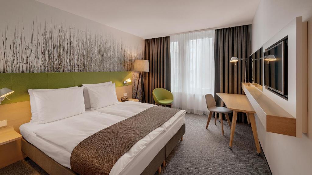 Quarto do Holiday Inn Frankfurt Alte Oper em Frankfurt com detalhes verdes e mesa de trabalho