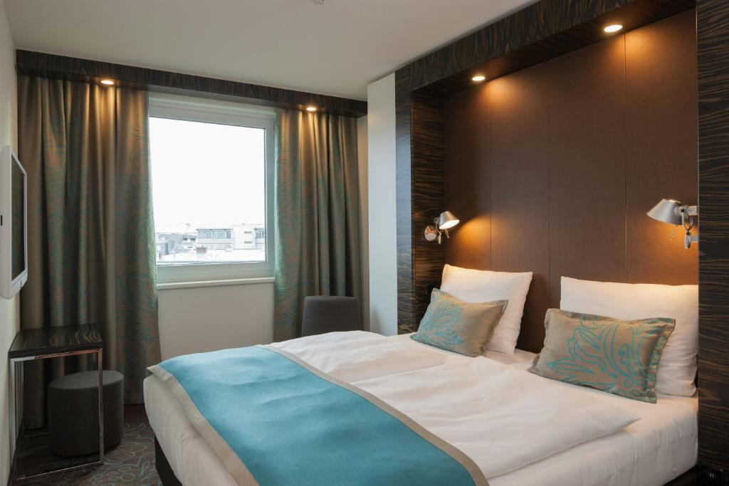 Quarto do Motel One Frankfurt Messe com detalhes em azul-claro e marrom