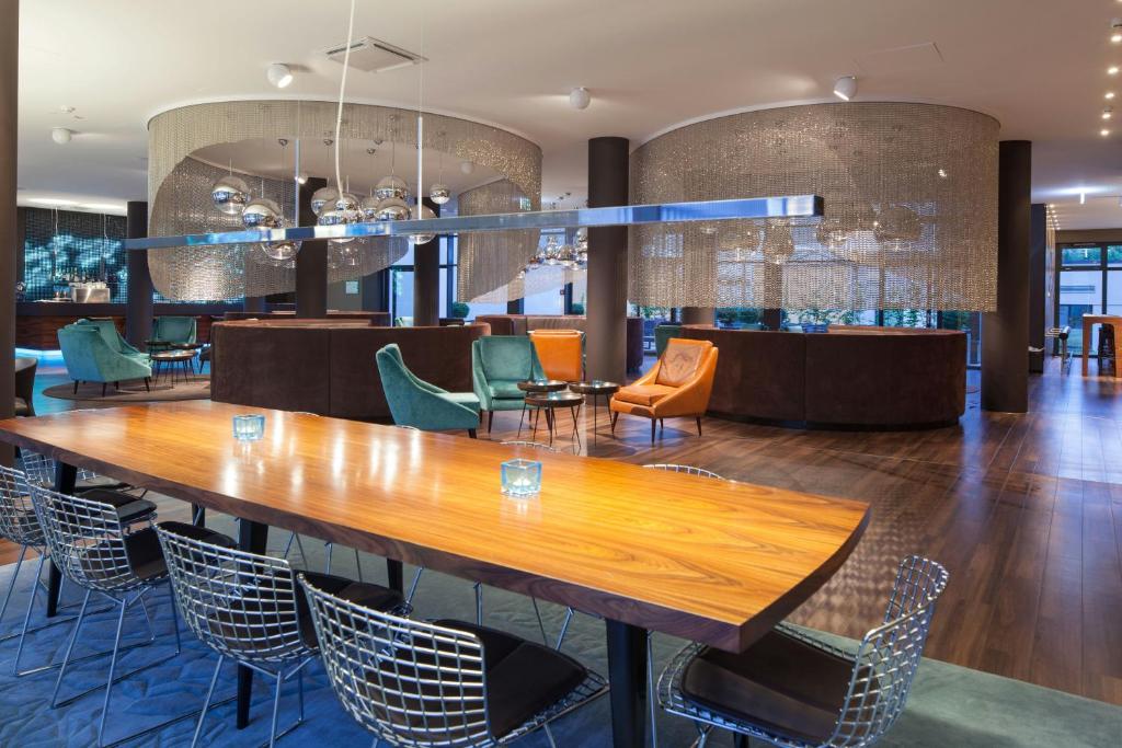 Lobby do Motel One Frankfurt Messe com mesas grandes e poltronas coloridas