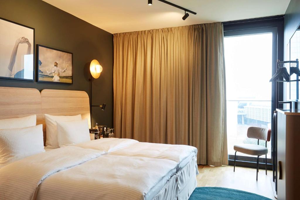 Quarto do Scandic Frankfurt Hafenpark em Frankfurt com cama de casal e cortinas bege