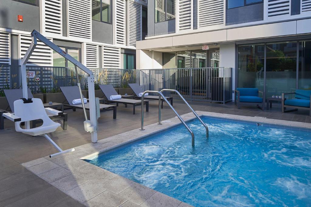 Piscina do Hotel Mariposa com espreguiçadeiras, área de descanso e prédio ao redor