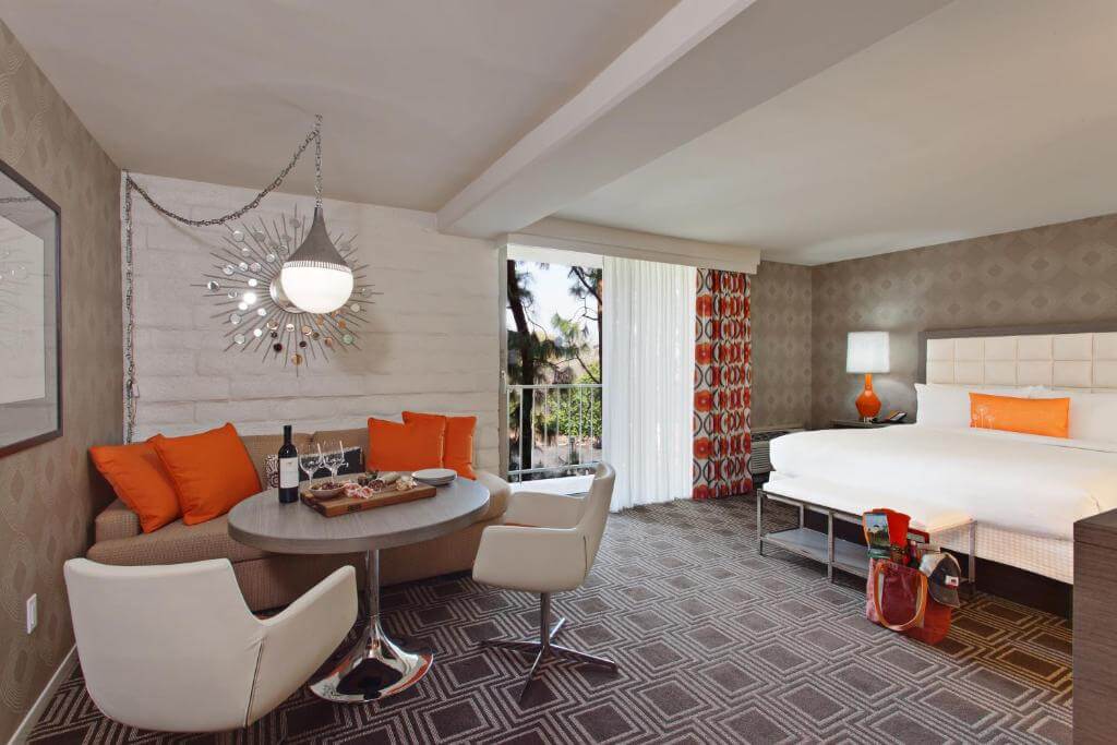 Quarto do The Garland com cama grande, mesa redonda, sofá e decoração em tons de laranja