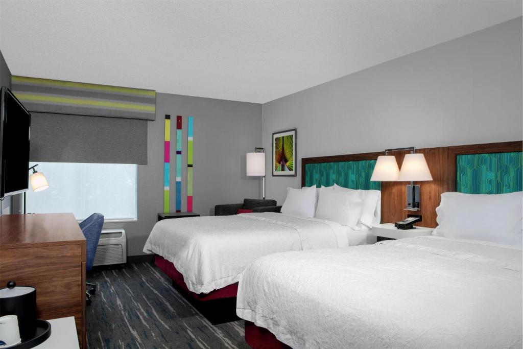 Quarto do Hampton Inn Lake Buena Vista com duas camas de casal, cabeceiras coloridas e mesa de trabalho perto da janela
