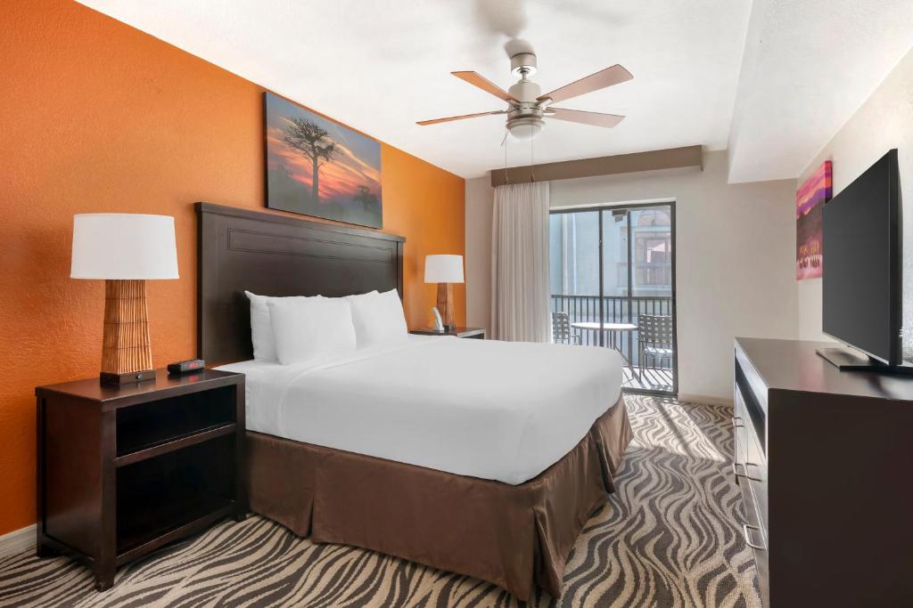 Quarto do Parkway International Resort Orlando com cama grande, varanda e decoração em tons de laranja