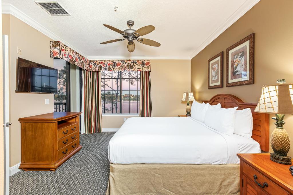 Quarto do The Berkley Orlando com cama grande, móveis de madeira e cortinas estampadas