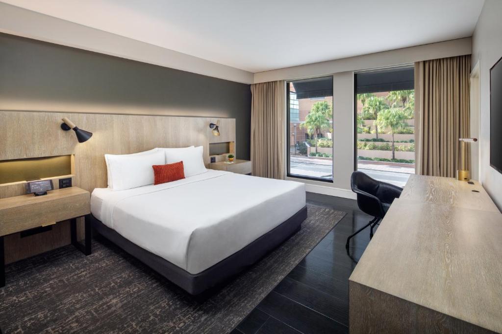 Quarto do The Delaney Hotel com cama grande, decoração em tons neutros e janelas amplas