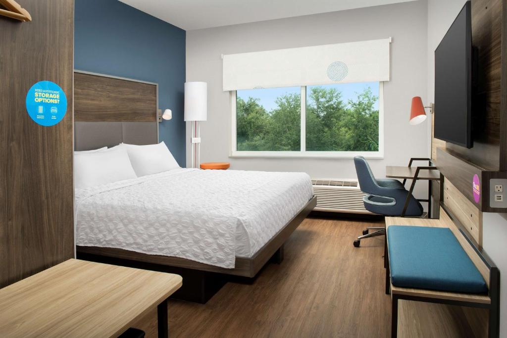 Quarto do Tru by Hilton Orlando Convention Center com cama grande, bancada de trabalho e janela com vista para árvores