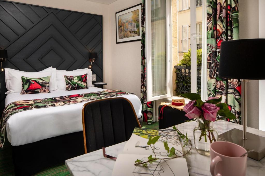 Quarto do Hotel des Arts Montmartre, com cama de casal, cabeceira preta, mesa de mármore e janela aberta para a rua