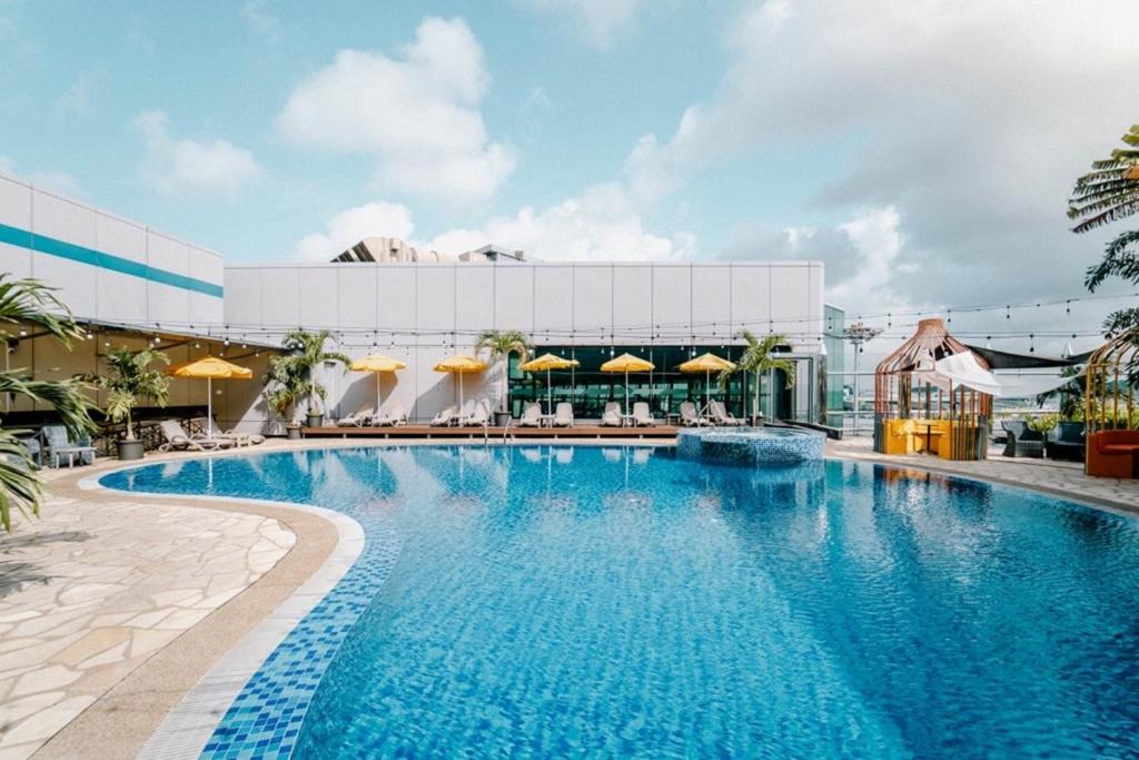 Piscina do Aerotel Singapore Transit Hotel in Terminal 1 em Singapura com espreguiçadeiras e guarda-sóis