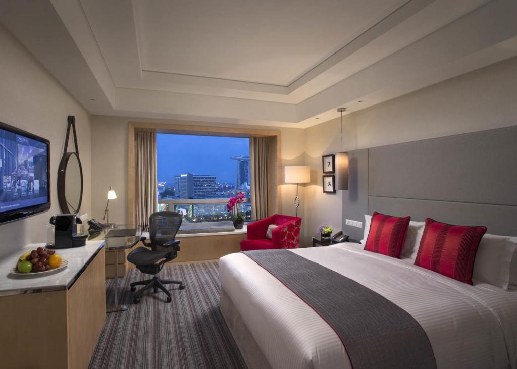 Quarto do Carlton Hotel Singapore em Singapura com detalhes em vermelho e vista urbana