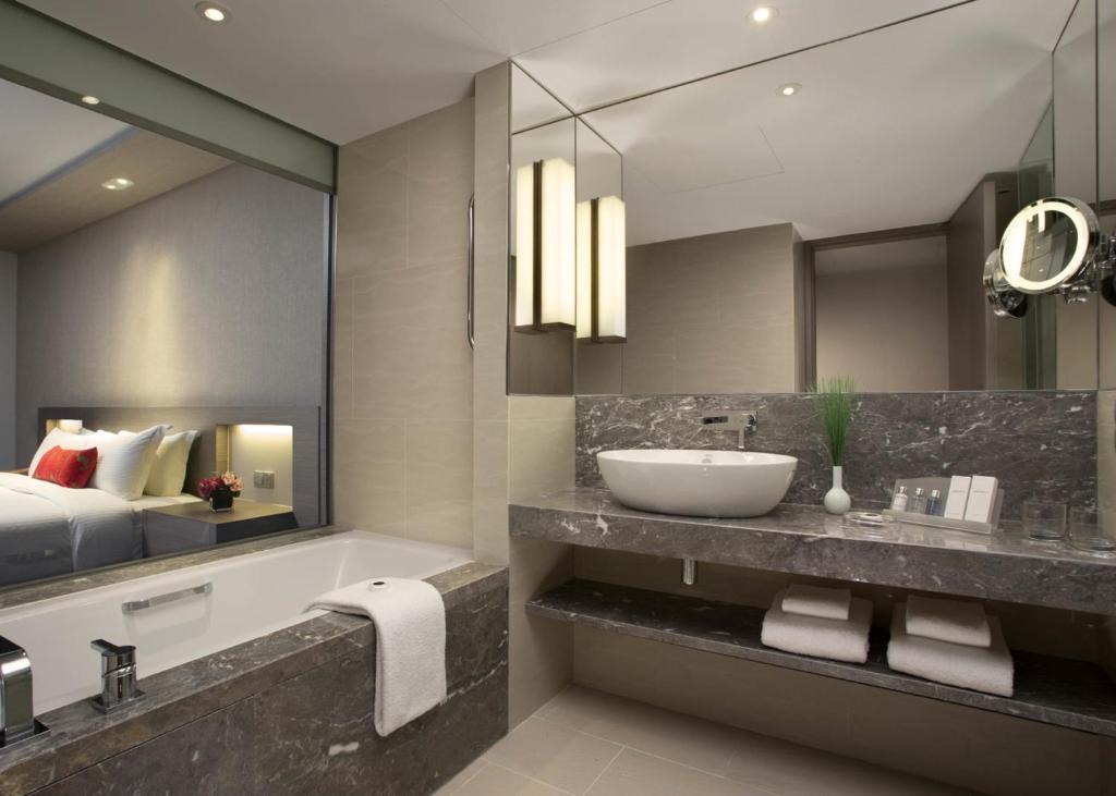 Banheiro do Carlton Hotel Singapore em Singapura com banheira e bancada de mármore