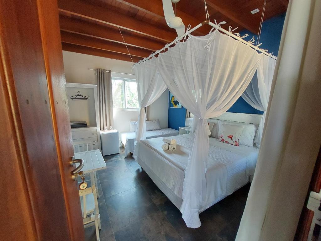 Quarto da Magias de Paraty Ecopousada em Trindade com cama com mosquiteiro e decoração em madeira