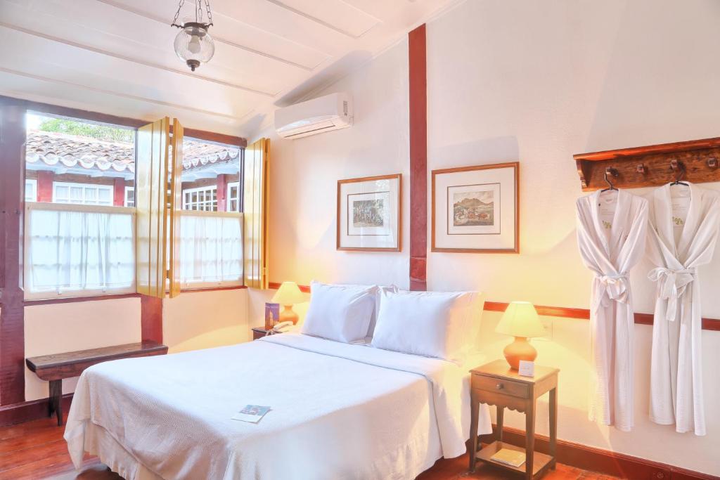 Quarto da Pousada do Ouro em Trindade com cama de casal, luminárias e janelas abertas