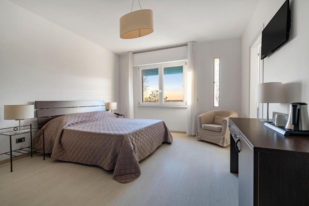 Quarto do Hotel Sorriso em Veneza com cama de casal e poltrona clara