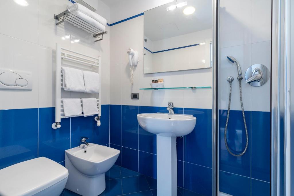 Banheiro do Hotel Sorriso em Veneza com azulejos azuis e box de vidro