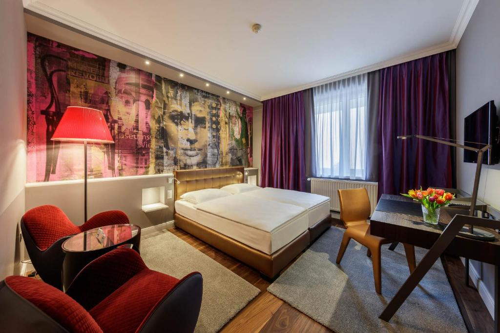 Quarto do Der Wilhelmshof em Viena com mural artístico e poltronas vermelhas