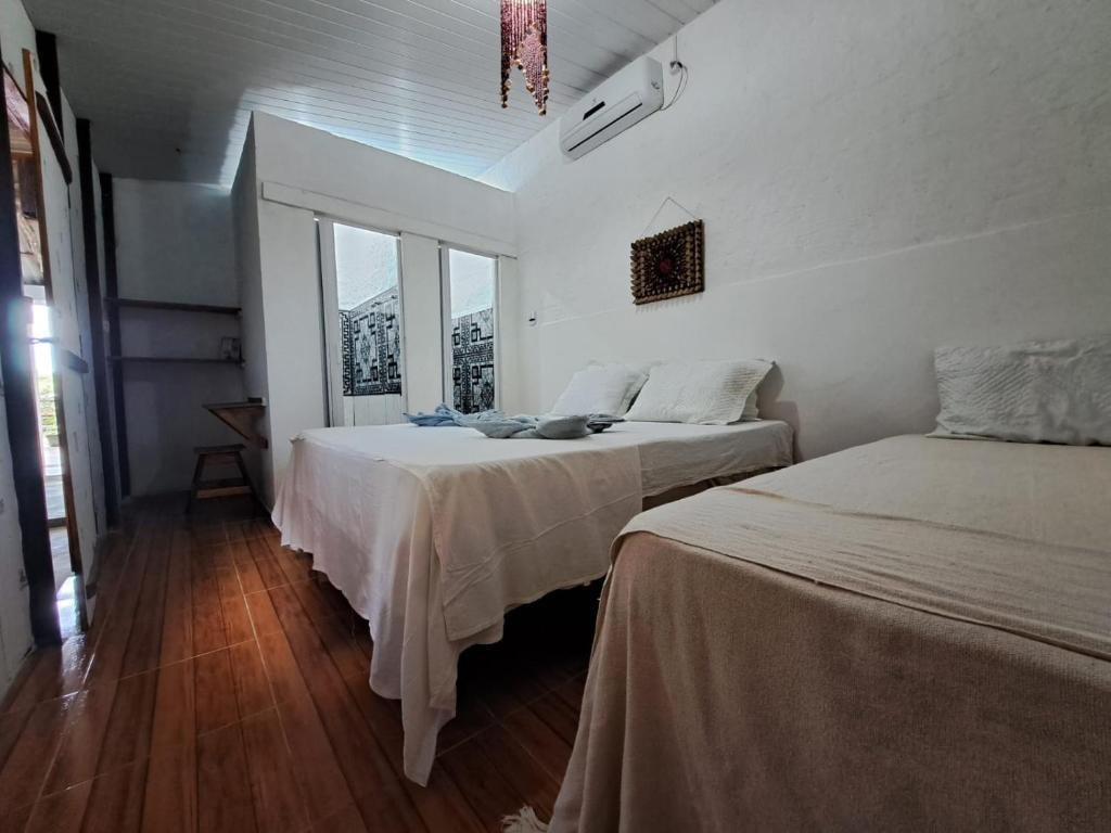 Quarto da Estresse Zero com cama de casal, cama de solteiro e decoração simples em tons claros