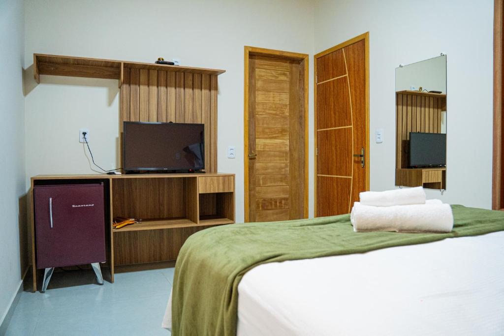 Quarto da Pousada Amorim com cama de casal, televisão e móveis de madeira