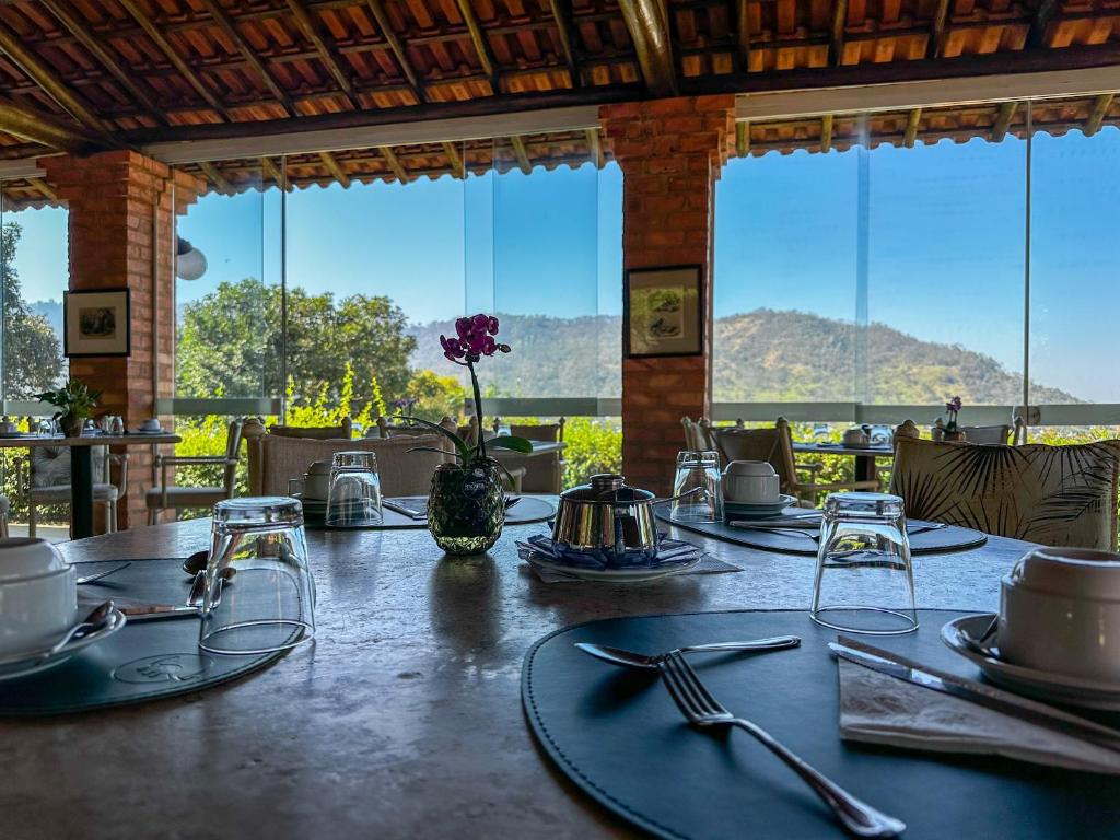 Área de café da manhã da Pousada Vale do Dinossauro em Águas de São Pedro com mesas postas e vista para a natureza