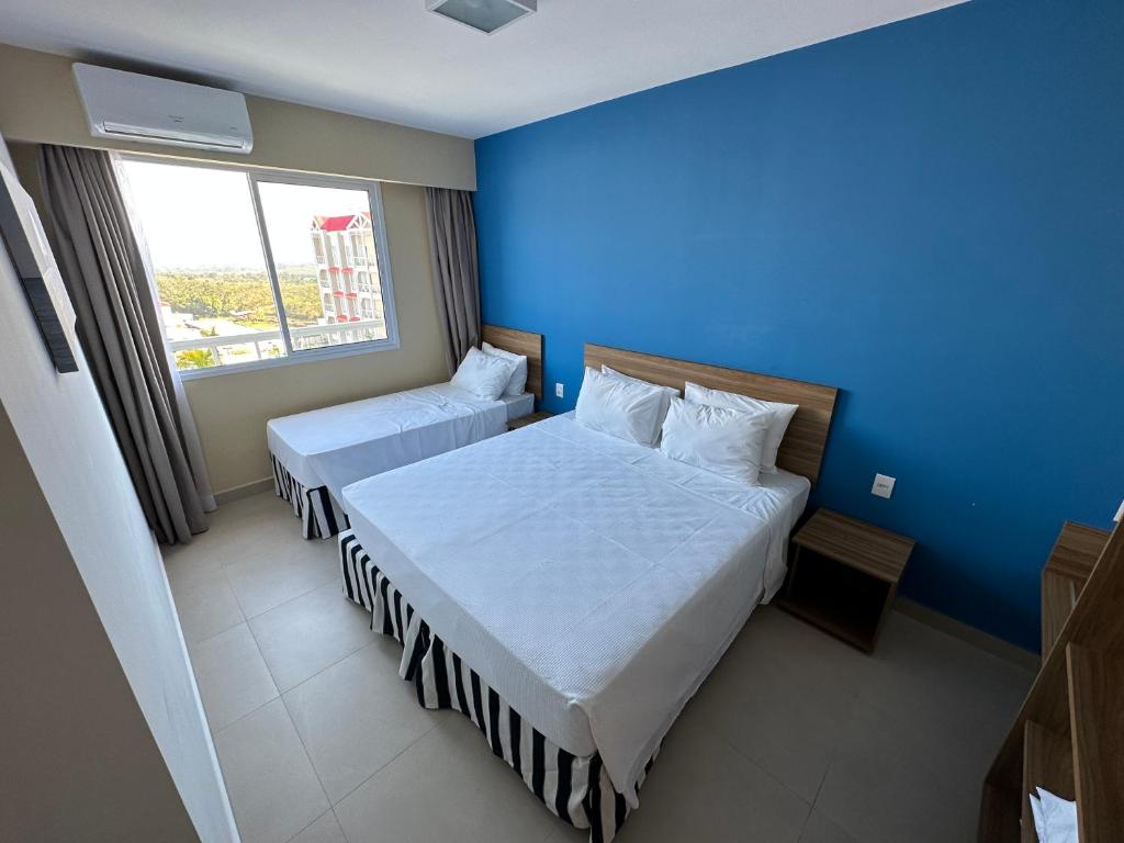 Quarto do São Pedro Thermas Resort Oficial em Águas de São Pedro com cama de casal, cama de solteiro e parede azul