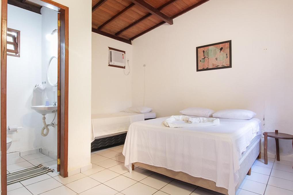 Quarto dos Novos Baianos Hostel e Pousada em Arraial d’Ajuda com cama de casal e banheiro integrado