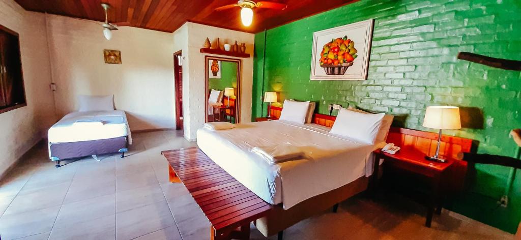 Quarto do Porto Preguiças Resort com parede verde, cama de casal e cama de solteiro