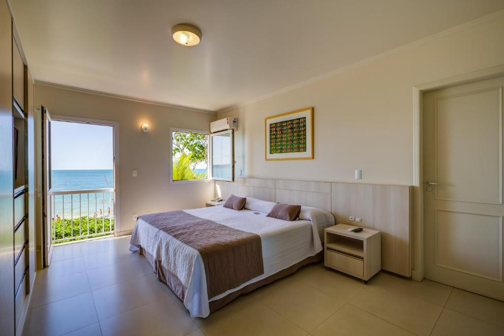 Quarto do Hotel Vila do Farol em Bombinhas com cama de casal, varanda e vista para o mar