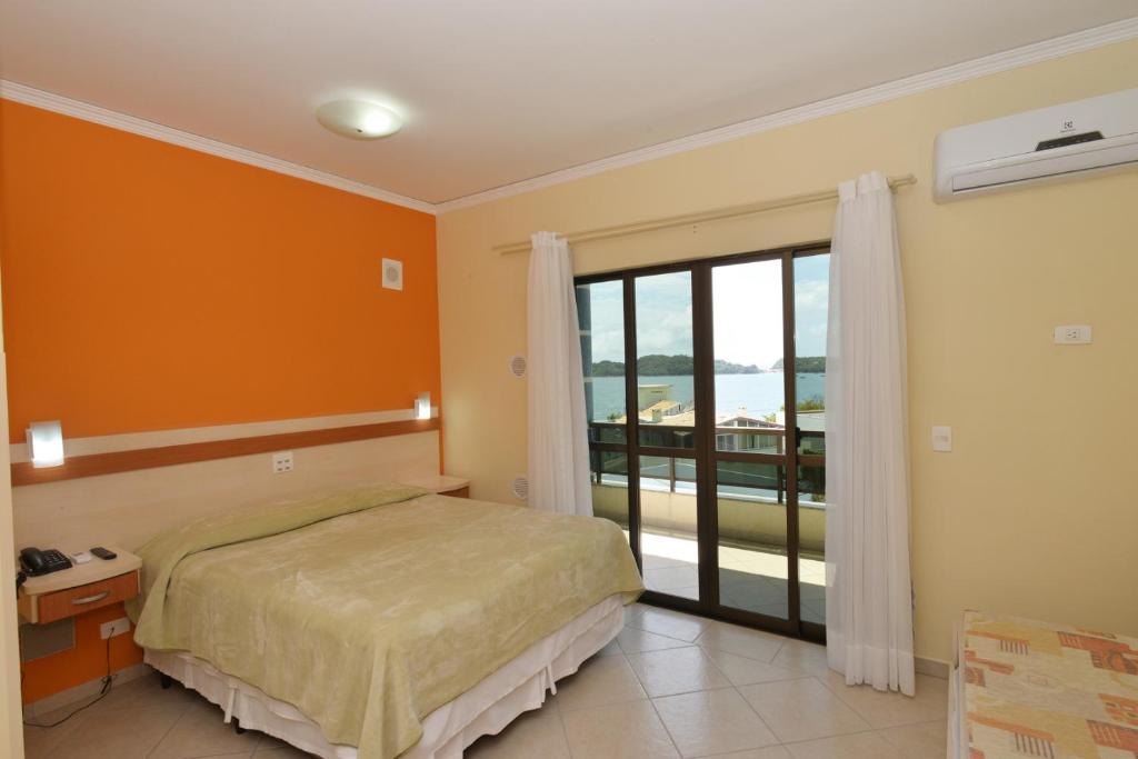 Quarto do Refúgio Costeiro II em Bombinhas com cama de casal, varanda e parede laranja