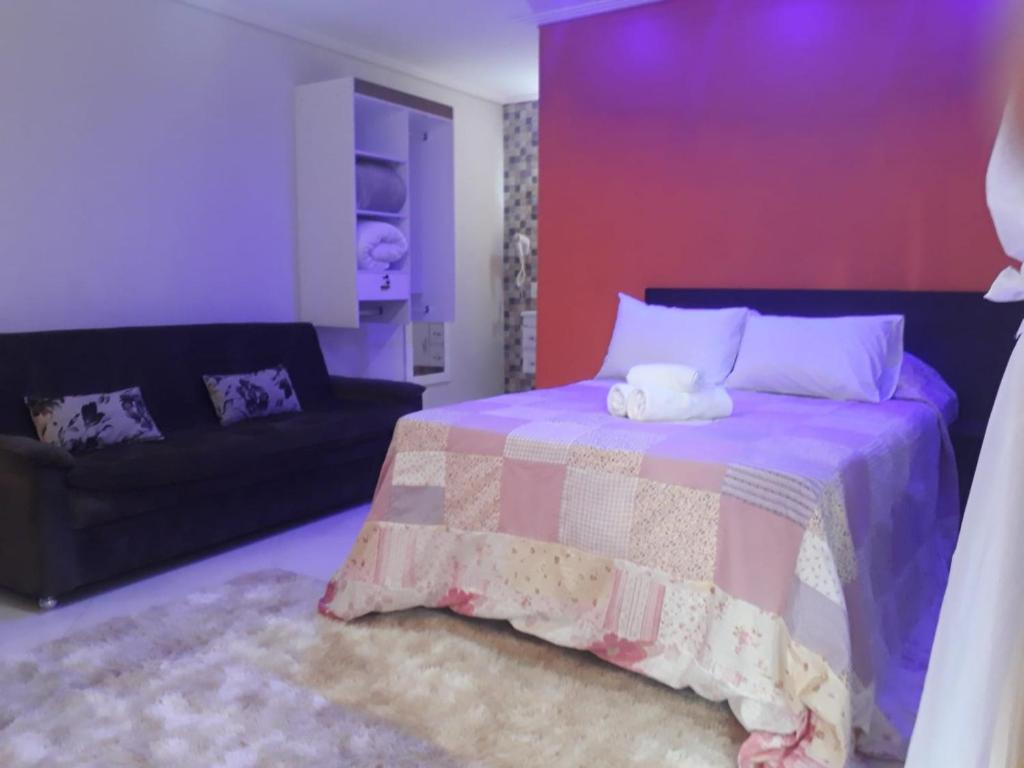 Suíte da Parada Di Maria Guest House com iluminação roxa e sofá preto