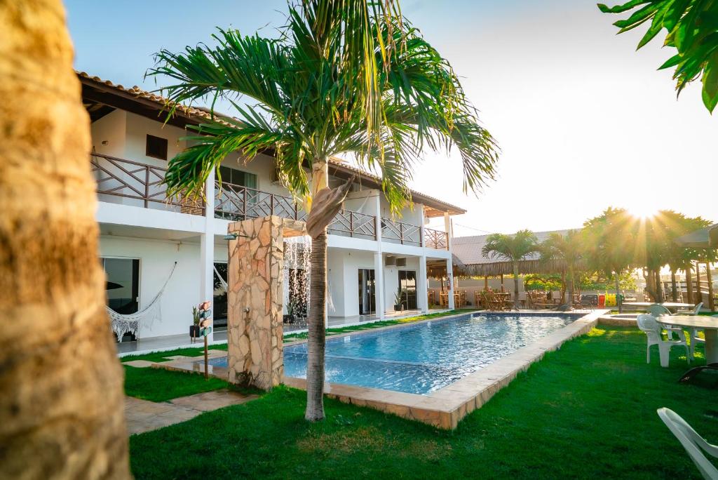Área externa do Milano Hotel Pousada Canoa Quebrada com piscina, jardim e prédio de dois andares