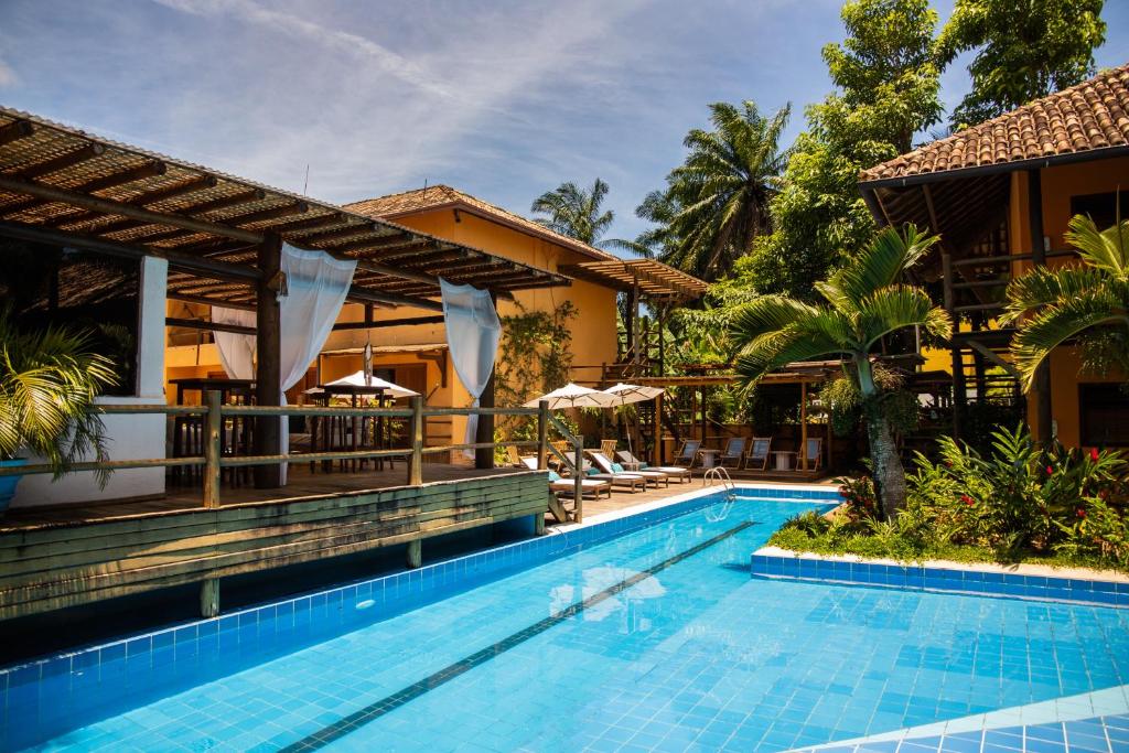 Piscina da Pousada Vila do Dengo em Itacaré cercada por coqueiros e área de descanso