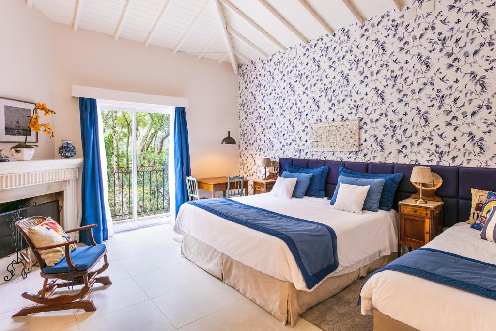 Quarto da Locanda Della Mimosa em Itaipava com duas camas, lareira e decoração elegante em tons de azul e branco
