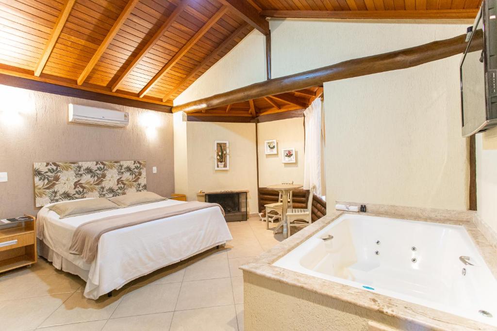 Quarto da Pousada Cantagalo em Itaipava com cama de casal, banheira de hidromassagem e teto de madeira
