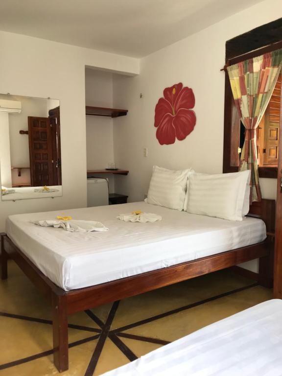 Quarto da Pousada Bangalô com cama de madeira e flor vermelha decorativa na parede