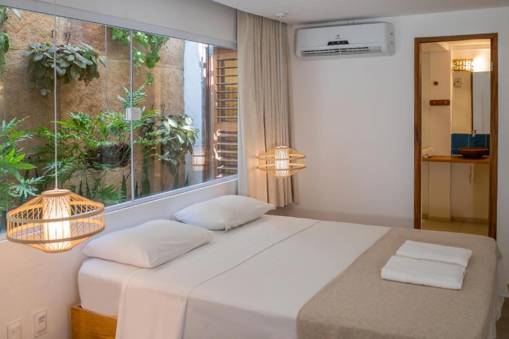 Quarto da Pousada Chez Toi com janela ampla voltada para jardim interno
