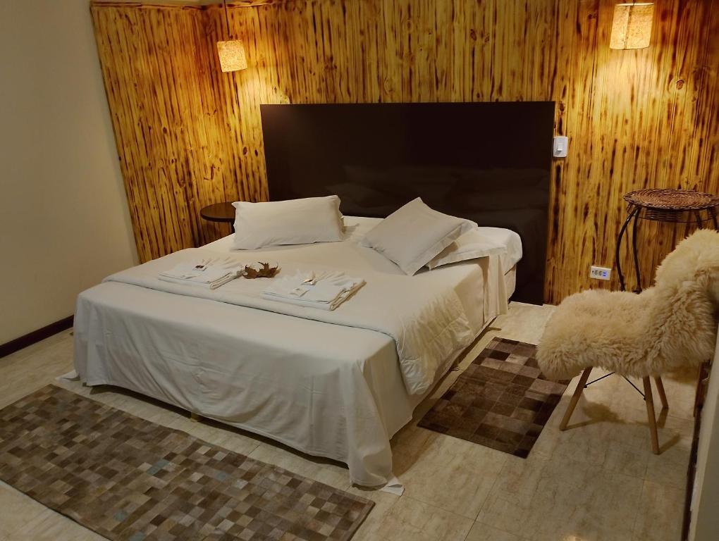 Quarto aconchegante na Pousada Le Lieu em Santo Antônio do Pinhal, cama com roupa branca e parede de madeira