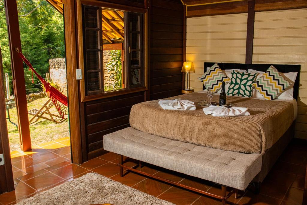 Quarto rústico na Pousada Olivier da Montanha em Santo Antônio do Pinhal, cama de casal com decoração e varanda com rede