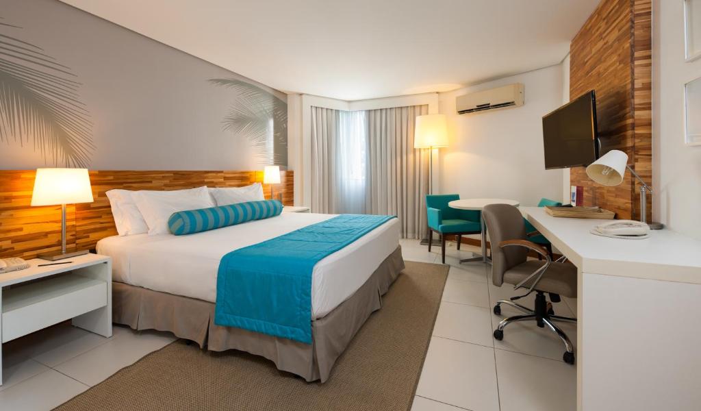 Quarto do Best Western Premier Maceió com cama de casal, decoração moderna e mesa de trabalho.