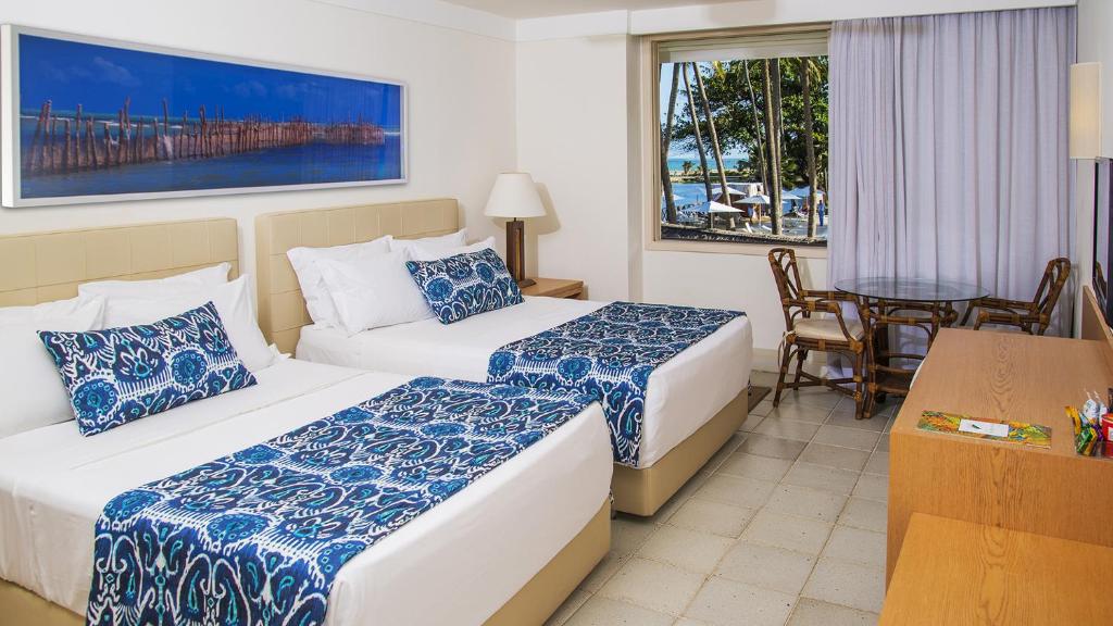 Quarto do Jatiúca Hotel e Resort com duas camas de casal e janela com vista para a praia