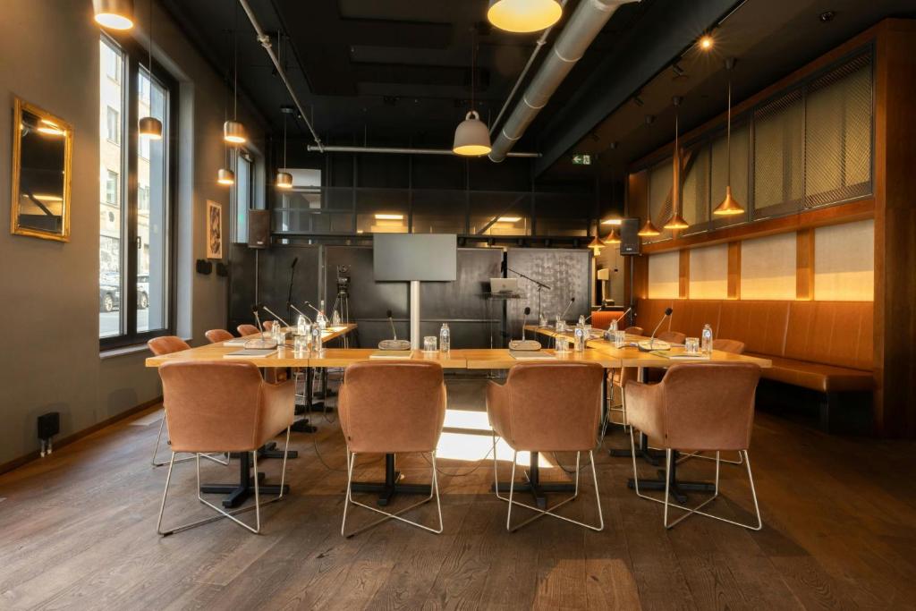 Sala de reuniões do Moxy Brussels City Center em Bruxelas com mesa comprida e cadeiras estofadas.