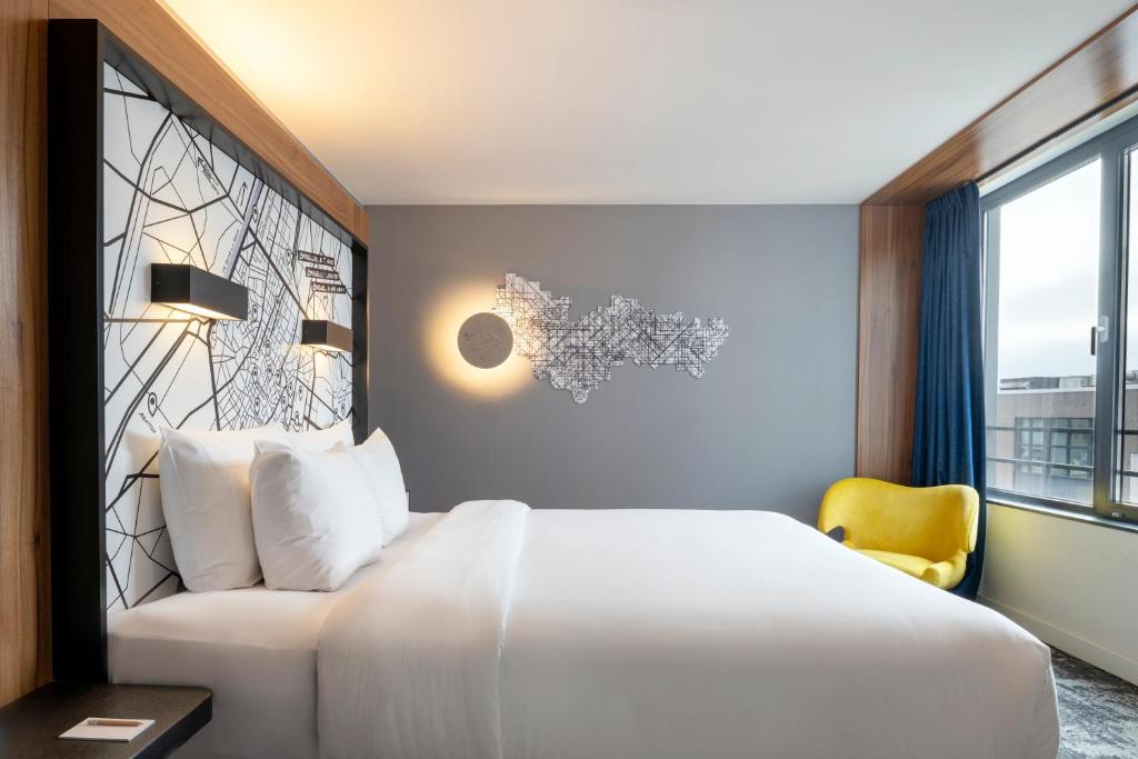 Quarto do Pestana Brussels Schuman em Bruxelas com cama de casal, poltrona amarela e janela ampla.