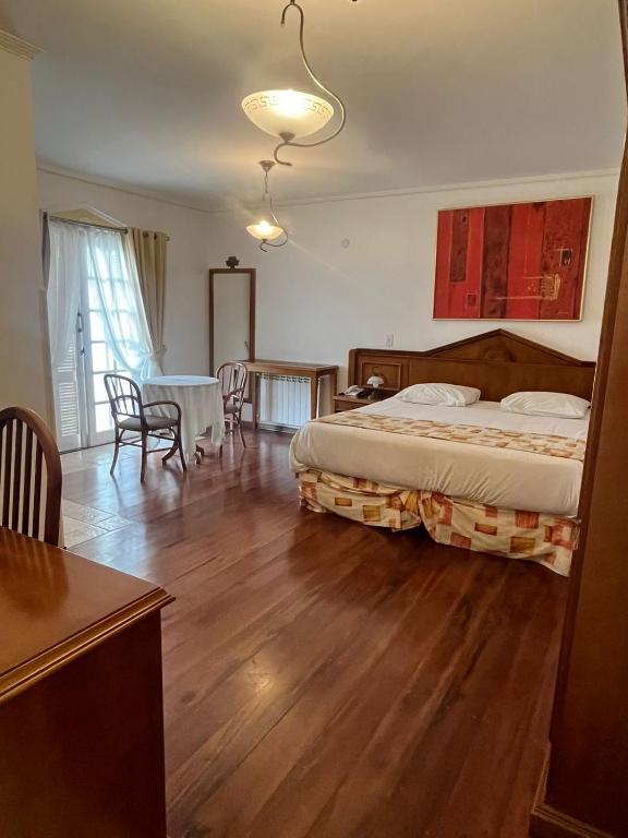 Suíte da Pousada Dom Alfredo José em Campos do Jordão com cama de casal e área de estar.