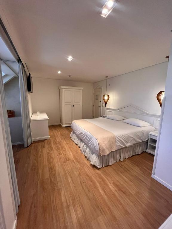 Quarto da Pousada Dom Alfredo José em Campos do Jordão com cama de casal e decoração em tons claros.