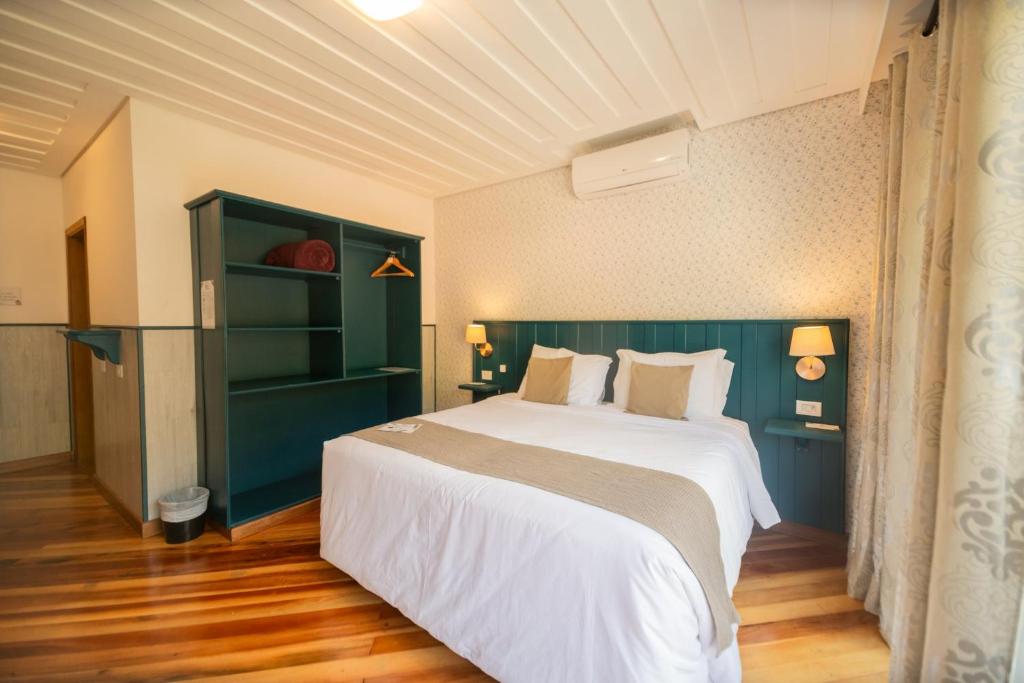 Quarto da Pousada Santa Felicidade em Campos do Jordão com cama de casal e móveis em azul escuro.