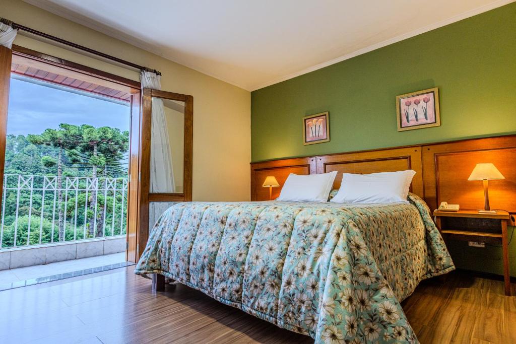 Quarto da Pousada Village Inn Capivari by National Inn em Campos do Jordão com varanda e vista para a natureza.